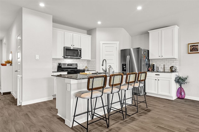 225 Big Spring Dr, Anahuac, TX 77514 - kitchen with appliances with stainless steel finishes, a breakfast bar, backsplash, a center island with sink, and wood finished floors