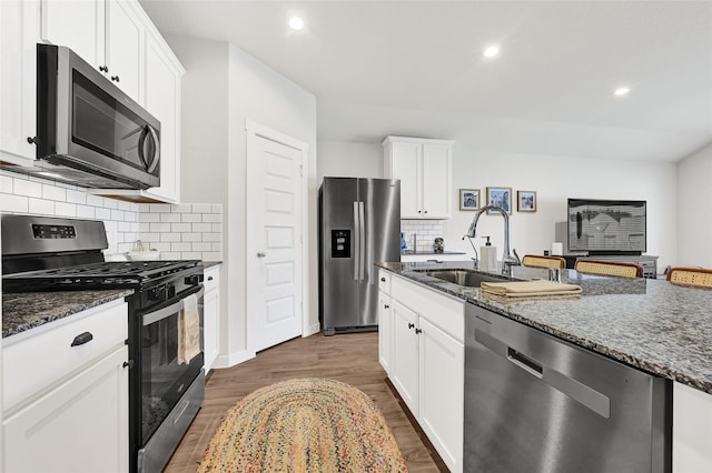 225 Big Spring Dr, Anahuac, TX 77514 - kitchen featuring appliances with stainless steel finishes, dark stone counters, wood finished floors, decorative backsplash, and recessed lighting