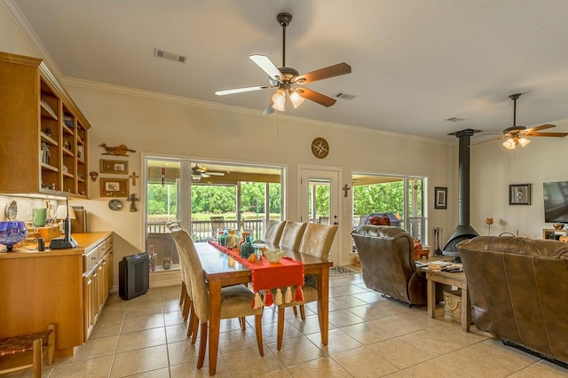 33 Lakeside, Trinity, TX 75862 - dining room featuring a ceiling fan, a wood stove, crown molding, and light tile patterned floors
