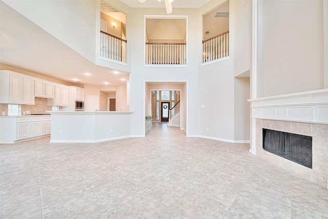 1814 Ferndale Lake Ct, Richmond, TX 77406 - unfurnished living room featuring a tile fireplace, light tile patterned floors, a high ceiling, and stairs