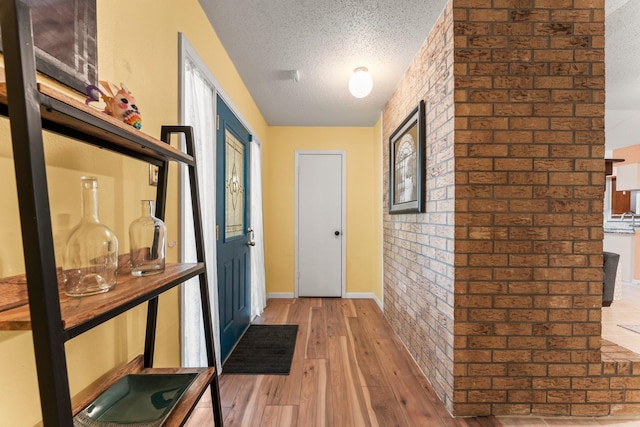 6103 Sunnygate Dr, Spring, TX 77373 - doorway with hardwood / wood-style flooring, brick wall, and a textured ceiling