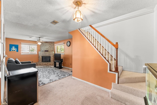 6103 Sunnygate Dr, Spring, TX 77373 - living area with ceiling fan, stairs, a textured ceiling, carpet, and a brick fireplace