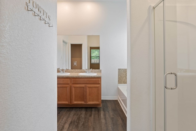 11053 Patriot Ct, Cleveland, TX 77328 - bathroom with wood finished floors, a shower stall, a garden tub, a textured wall, and double vanity