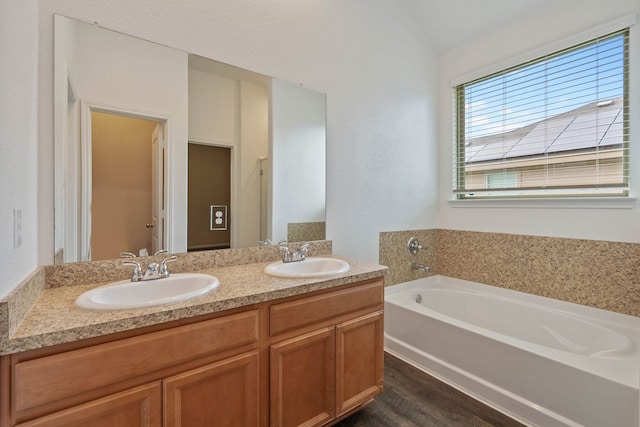 11053 Patriot Ct, Cleveland, TX 77328 - bathroom featuring a garden tub, double vanity, and wood finished floors