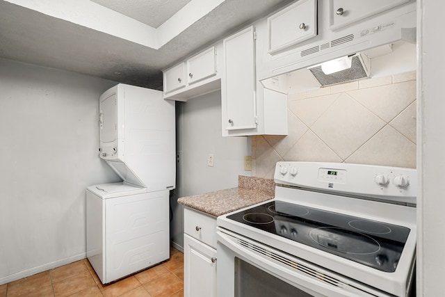 7700 Creekbend Dr Unit 6, Houston, TX 77071 - kitchen featuring white electric stove, under cabinet range hood, stacked washing machine and dryer, white cabinetry, and light tile patterned floors