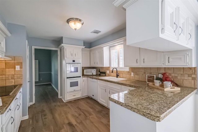 1711 Earl Of Dunmore St, Katy, TX 77449 - kitchen with white appliances, a peninsula, white cabinetry, tasteful backsplash, and dark wood finished floors