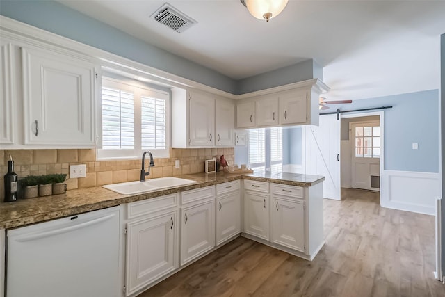 1711 Earl Of Dunmore St, Katy, TX 77449 - kitchen featuring dishwasher, white cabinetry, a wainscoted wall, a peninsula, and light wood-type flooring