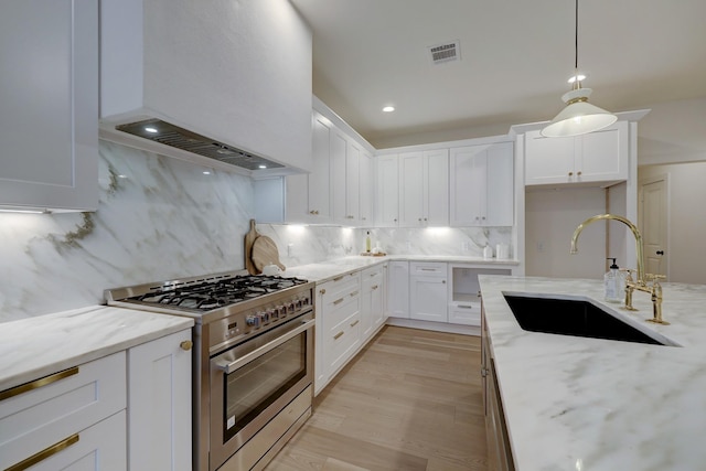 6110 Yarwell Dr, Houston, TX 77096 - kitchen with high end range, premium range hood, white cabinets, light stone counters, and recessed lighting
