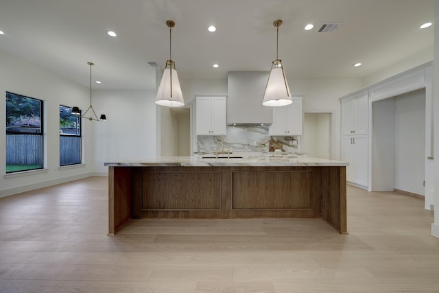 6110 Yarwell Dr, Houston, TX 77096 - kitchen with wall chimney exhaust hood, white cabinetry, light wood-style floors, backsplash, and recessed lighting