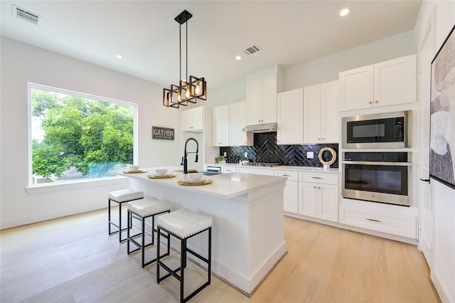 2310 Reinerman St, Houston, TX 77007 - kitchen with appliances with stainless steel finishes, tasteful backsplash, light wood finished floors, white cabinets, and recessed lighting