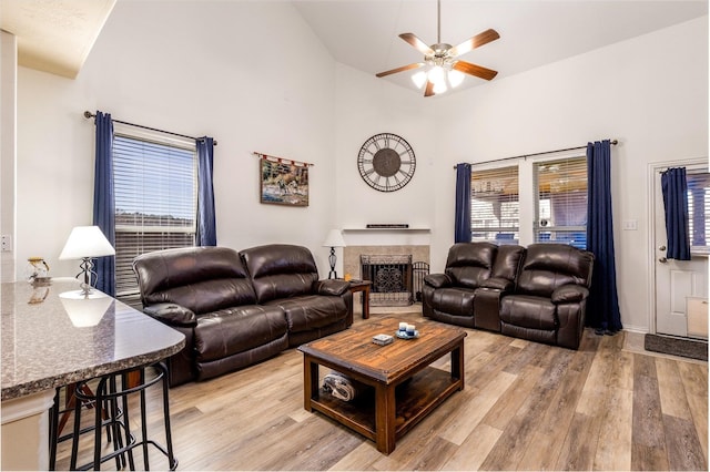 11443 Northam Dr, Tomball, TX 77375 - living area featuring ceiling fan, light wood-style floors, a fireplace with raised hearth, and high vaulted ceiling