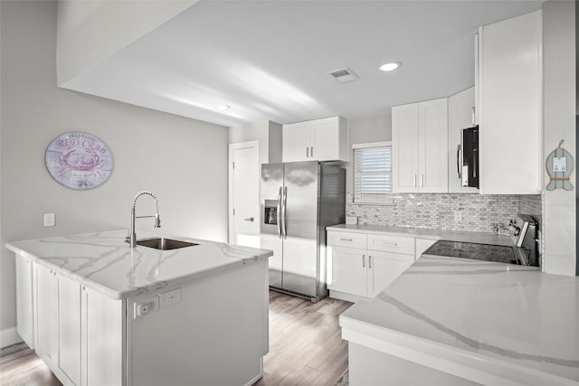 17711 Termini San Luis Pass Rd, Galveston, TX 77554 - kitchen with stainless steel appliances, light stone counters, light wood-type flooring, decorative backsplash, and white cabinets