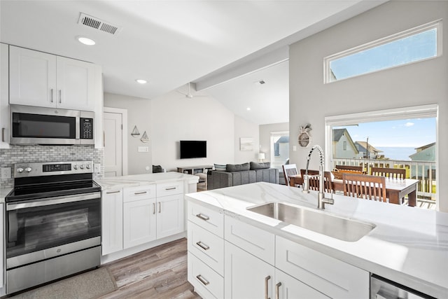 17711 Termini San Luis Pass Rd, Galveston, TX 77554 - kitchen with appliances with stainless steel finishes, light wood-style floors, white cabinets, tasteful backsplash, and recessed lighting