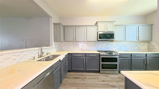 1855 Garnet Breeze Dr, Rosharon, TX 77583 - kitchen with appliances with stainless steel finishes, light wood-type flooring, backsplash, gray cabinetry, and light stone countertops