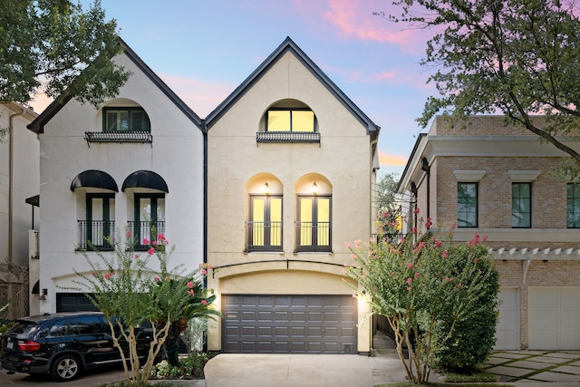 2217 Dunraven Ln, Houston, TX 77019 - view of front facade featuring a garage, driveway, a balcony, and stucco siding