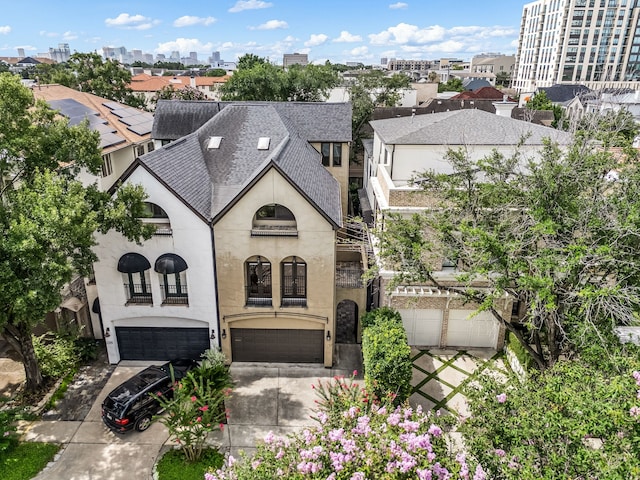 2217 Dunraven Ln, Houston, TX 77019 - view of front facade featuring roof with shingles, an attached garage, concrete driveway, stucco siding, and a balcony