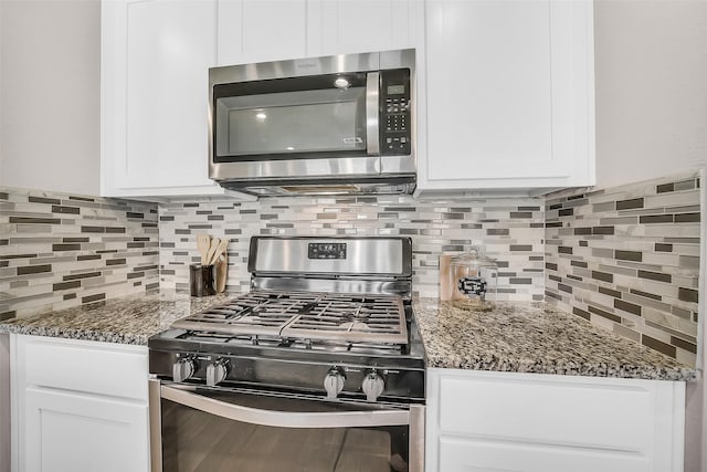 4310 Fornari Ln, Katy, TX 77449 - kitchen with stainless steel appliances, white cabinetry, backsplash, and dark stone countertops