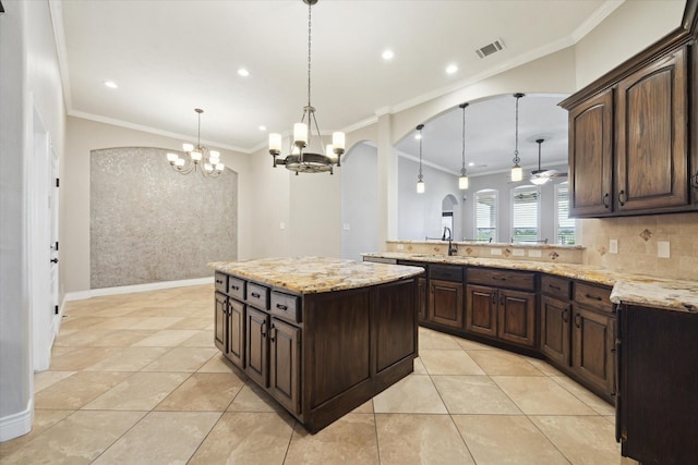 2508 Siskin Trl, League City, TX 77573 - kitchen with a chandelier, arched walkways, ornamental molding, dark brown cabinets, and pendant lighting