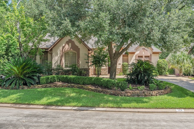 102 W Racing Cloud Ct, The Woodlands, TX 77381 - view of front of home featuring stucco siding, stone siding, a front yard, and driveway