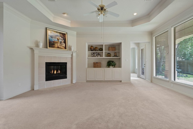 102 W Racing Cloud Ct, The Woodlands, TX 77381 - unfurnished living room with plenty of natural light, crown molding, a raised ceiling, a fireplace, and light carpet