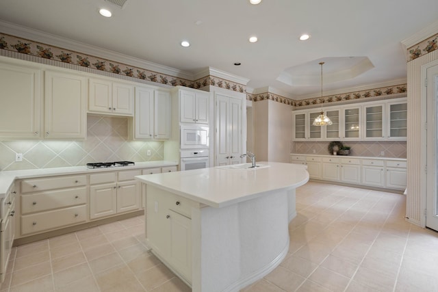 102 W Racing Cloud Ct, The Woodlands, TX 77381 - kitchen with white appliances, decorative backsplash, an island with sink, light countertops, and glass insert cabinets