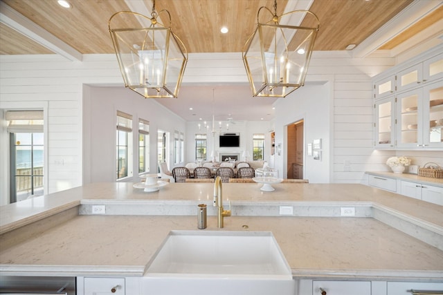 4223 Swashbuckle, Galveston, TX 77554 - kitchen with a wooden ceiling with exposed beams, open floor plan, a chandelier, light stone countertops, and white cabinetry