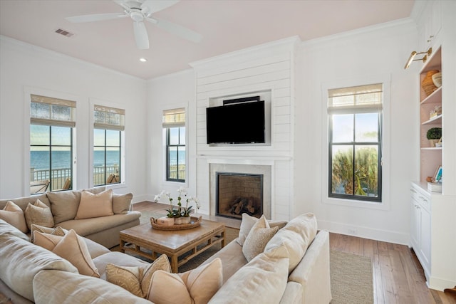 4223 Swashbuckle, Galveston, TX 77554 - living room featuring crown molding, healthy amount of natural light, a ceiling fan, light wood finished floors, and a large fireplace