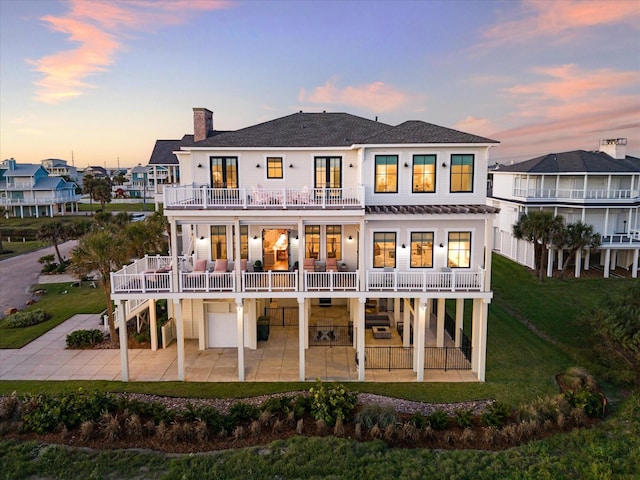 4223 Swashbuckle, Galveston, TX 77554 - back of property at dusk with a balcony, a patio, stairway, a yard, and a chimney