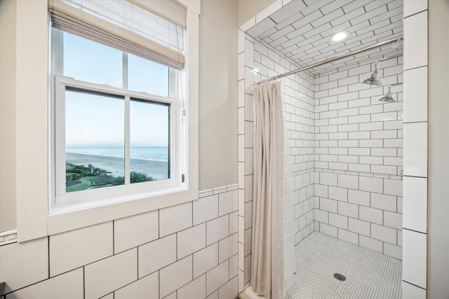 4223 Swashbuckle, Galveston, TX 77554 - bathroom featuring healthy amount of natural light, a stall shower, tile walls, a water view, and wainscoting