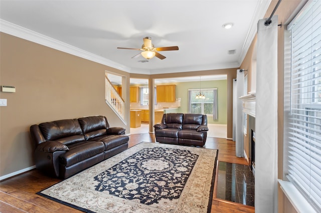 402 Starleaf Ln, Pearland, TX 77584 - living room with ceiling fan, ornamental molding, stairway, a fireplace with flush hearth, and dark wood-type flooring