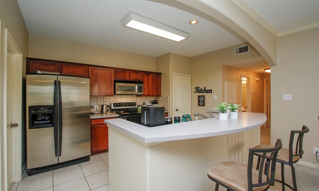 6607 Lake Woodlands Dr Unit 223, The Woodlands, TX 77382 - kitchen featuring appliances with stainless steel finishes, a breakfast bar, tasteful backsplash, arched walkways, and light countertops