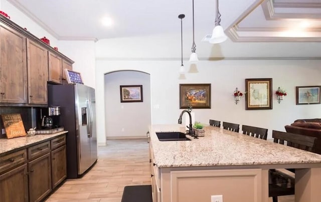 2977 Presidio Cir, Belton, TX 76513 - kitchen featuring a kitchen breakfast bar, light wood-style floors, stainless steel refrigerator with ice dispenser, arched walkways, and a kitchen island with sink