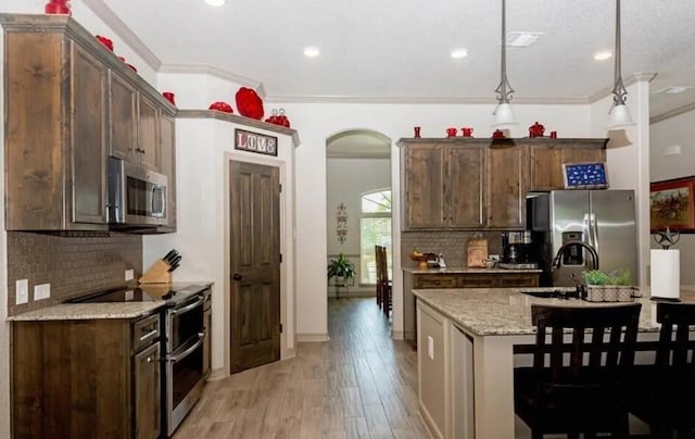 2977 Presidio Cir, Belton, TX 76513 - kitchen with appliances with stainless steel finishes, tasteful backsplash, light wood finished floors, crown molding, and dark brown cabinetry
