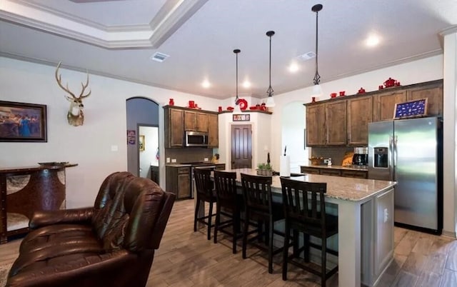 2977 Presidio Cir, Belton, TX 76513 - kitchen featuring appliances with stainless steel finishes, arched walkways, a kitchen island, light wood-style floors, and backsplash
