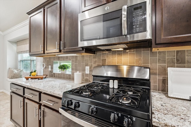 31703 Morning Ridge Ln, Spring, TX 77386 - kitchen with appliances with stainless steel finishes, crown molding, dark brown cabinetry, backsplash, and light stone countertops