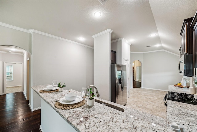 31703 Morning Ridge Ln, Spring, TX 77386 - kitchen with arched walkways, appliances with stainless steel finishes, light stone countertops, crown molding, and a textured ceiling