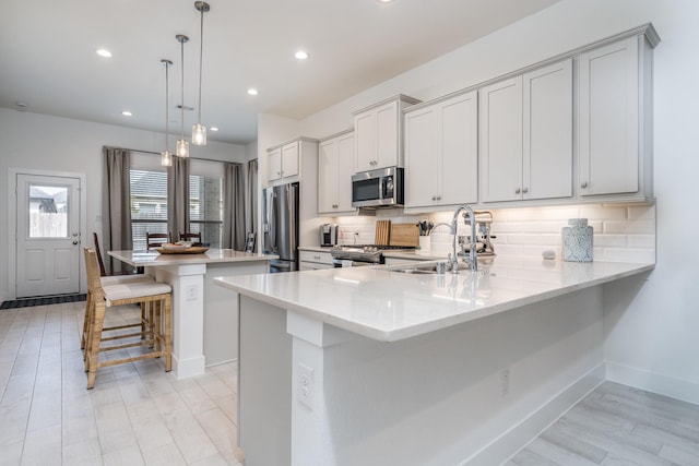17746 Tree Of Heaven, Conroe, TX 77385 - kitchen with stainless steel appliances, a kitchen bar, backsplash, recessed lighting, and light wood-style flooring
