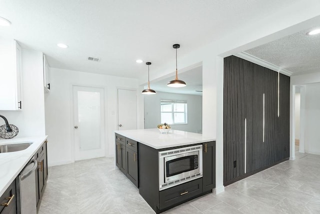 28926 Twisted Oak Dr, Shenandoah, TX 77381 - kitchen with appliances with stainless steel finishes, white cabinetry, light stone counters, hanging light fixtures, and a textured ceiling