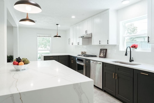 28926 Twisted Oak Dr, Shenandoah, TX 77381 - kitchen featuring stainless steel appliances, white cabinets, light stone counters, decorative light fixtures, and a peninsula