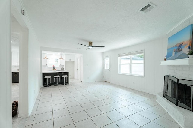 28926 Twisted Oak Dr, Shenandoah, TX 77381 - unfurnished living room with a ceiling fan, a fireplace, light tile patterned floors, and a textured ceiling