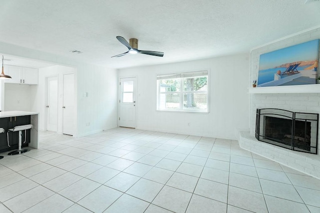 28926 Twisted Oak Dr, Shenandoah, TX 77381 - unfurnished living room featuring a ceiling fan, a brick fireplace, a textured ceiling, and light tile patterned floors