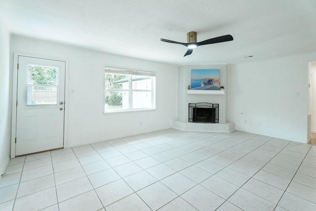 28926 Twisted Oak Dr, Shenandoah, TX 77381 - unfurnished living room featuring ceiling fan, a fireplace, a textured ceiling, and light tile patterned floors