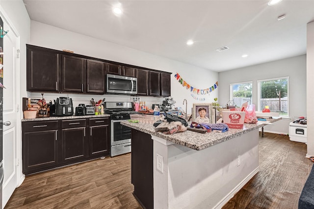 2435 Palmer Lake Ln, Spring, TX 77373 - kitchen with stainless steel appliances, recessed lighting, dark wood finished floors, light stone countertops, and an island with sink
