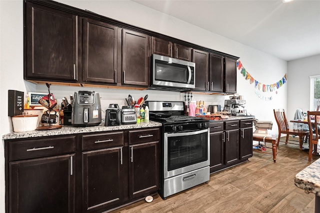 2435 Palmer Lake Ln, Spring, TX 77373 - kitchen featuring appliances with stainless steel finishes, light wood finished floors, light stone countertops, and dark brown cabinetry
