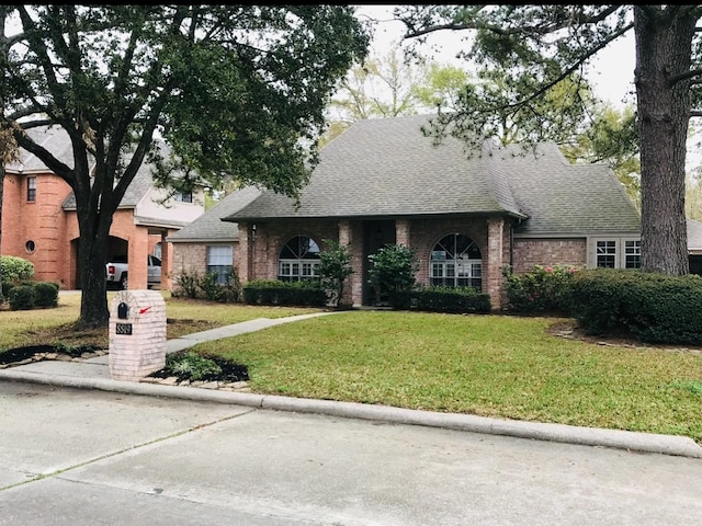 8819 W Rayford Rd, Tomball, TX 77375 - view of front of home with a shingled roof, a front yard, and brick siding