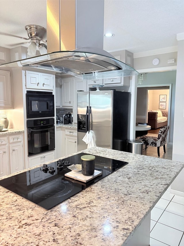8819 W Rayford Rd, Tomball, TX 77375 - kitchen with black appliances, island range hood, white cabinets, light stone counters, and a ceiling fan