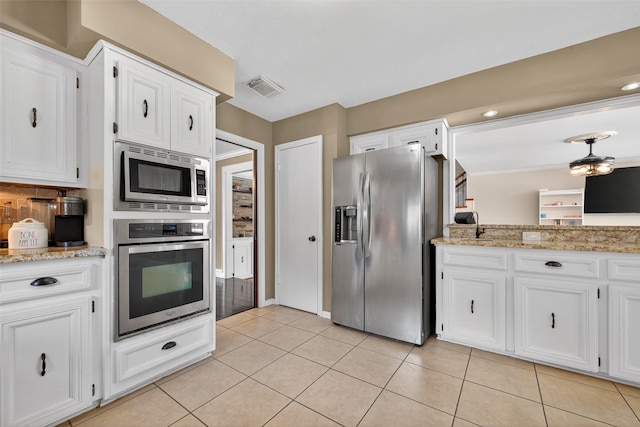 5903 Havenwoods Dr, Houston, TX 77066 - kitchen with appliances with stainless steel finishes, white cabinets, light tile patterned floors, and light stone countertops