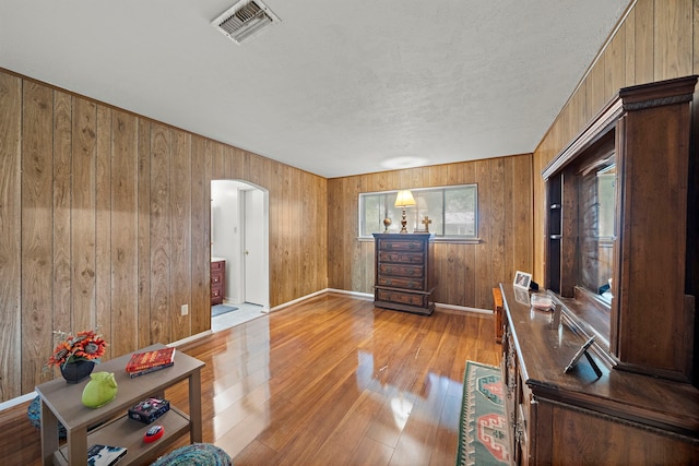 2121 Redwood St, Kemah, TX 77565 - foyer featuring arched walkways, light wood-type flooring, wood walls, and a textured ceiling