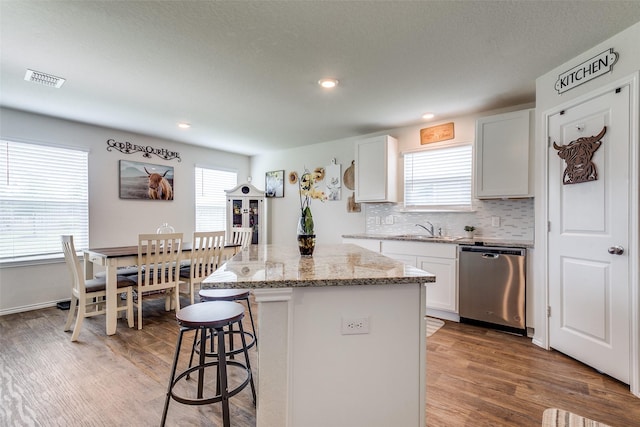 1007 Cozumel Emerald, San Antonio, TX 78253 - kitchen with dishwasher, a kitchen bar, a kitchen island, light wood finished floors, and light stone counters