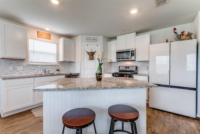 1007 Cozumel Emerald, San Antonio, TX 78253 - kitchen featuring appliances with stainless steel finishes, a kitchen bar, light wood-style flooring, white cabinetry, and a kitchen island